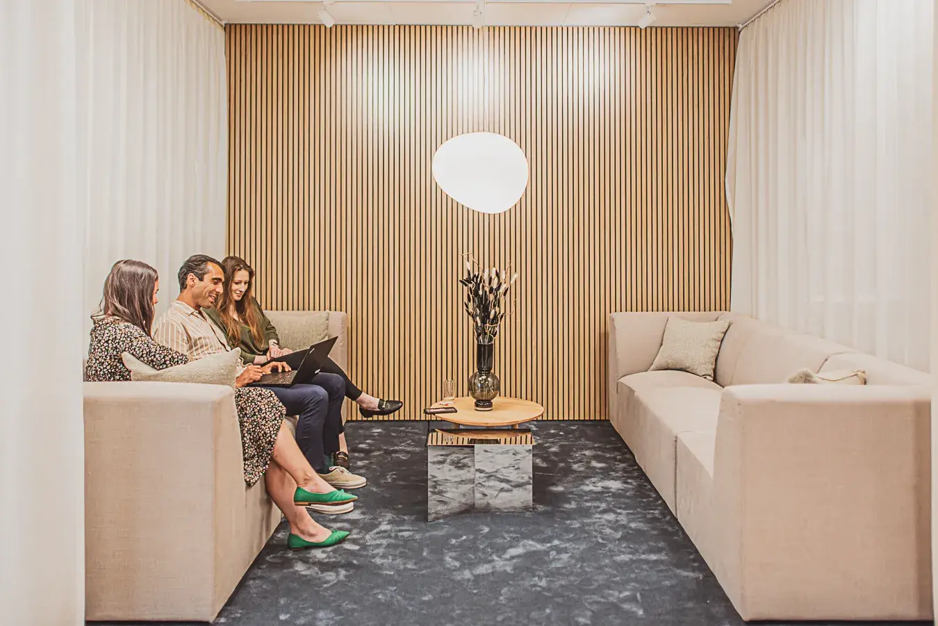 Tre medarbetare på Manpower sitter och arbetar med sina laptops i en soffa i receptionen på Manpowers kontor i Citygate