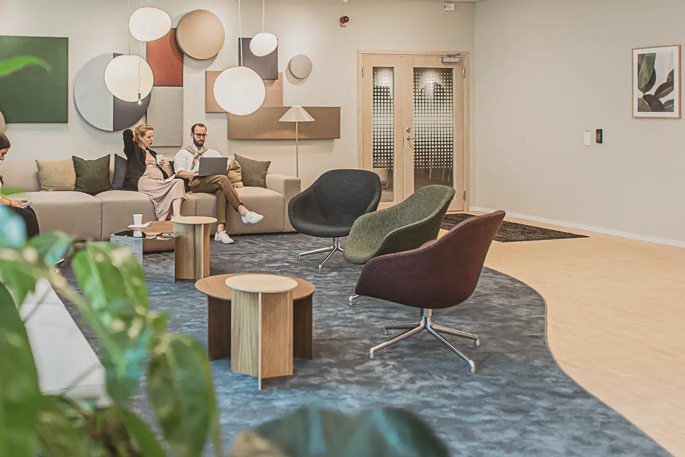 Två medarbetare på Manpower sitter och arbetar med sina laptops i en soffa i receptionen på Manpowers kontor i Citygate